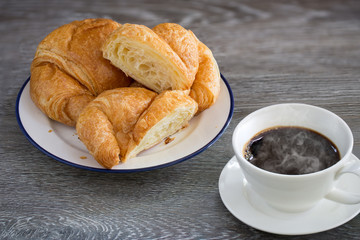 Butter Croissants in white dish and hot black coffee in the cup  on wooden table
