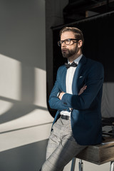 handsome young businessman in eyeglasses and bow tie looking away