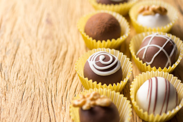 Assorted homemade chocolate truffles. Selective focus. Rustic wooden table.