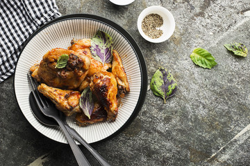 Appetizing chicken pieces in a hot sweet frosting baked in the oven in a baked pumpkin, sour cream and basil in a serving plate on a dark background. Top View