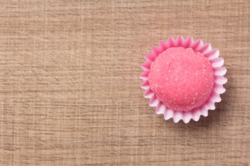 Bicho de pe is a strawberry flovoured brazilian candy. Children birthday party sweet. Flat lay design of candy ball over wood.