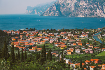 Beautiful panorama view of a mountain lake in northern Italy in the lombardy of lago di garda from a bird's eye view. View of the roofs of the city and the channel of Riva del Garda in summer