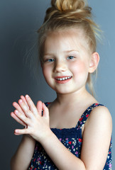 Portrait of a happy, positive, smiling, little girl, grey background