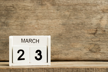 White block calendar present date 23 and month March on wood background