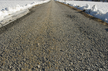 concept background: small mountain road of a village, asphalted, after a snowfall, cleaned from snow, snow fills the fields next to the asphalt, sun, isolated, solitude, life, roadtrip, winter, Italy