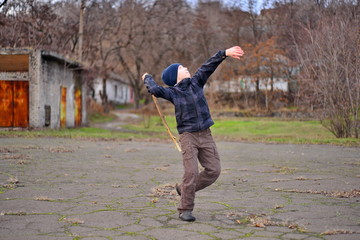 Fototapeta premium boy playing and jumping with stick in hand. Little boy playing in puddle in spring forest. happy childhood