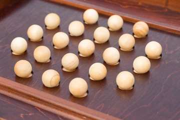 playing, entertainment, game concept. there are wooden balls of really small size that are placed in the round recess, they are made in surface of expensive good looking table