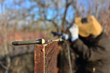 welder makes a fence in the street. Electric welder makes the fence in his own manor