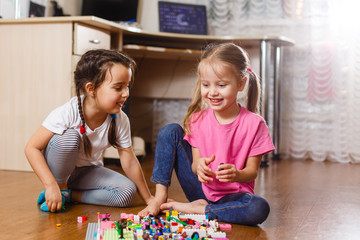 Two little children are playing with blocks happy girls at home funny lovely sisters