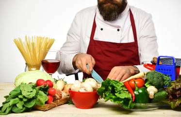 Cook with beard burgundy uniform cut vegetables. Professional cookery concept.