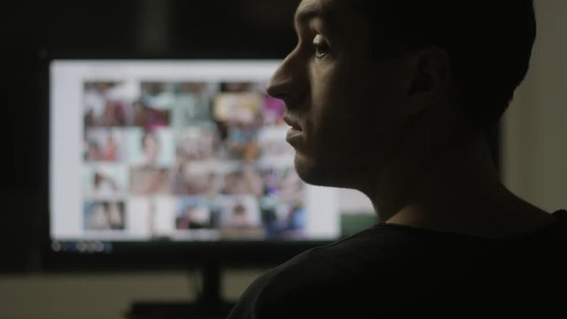 young man watching surfing pornography site on the web at night at home
