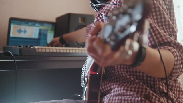 Young musician composes and records music playing the electric guitar using computer and keyboard