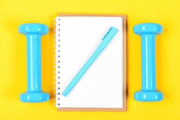 Weight loss and active lifestyle. Notebook, pen and gym equipment