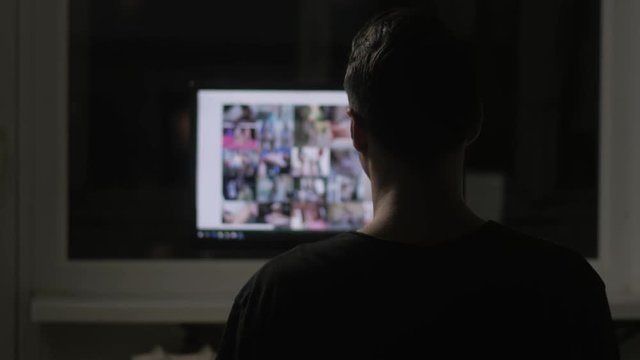 young man watching surfing pornography site on the web at night at home