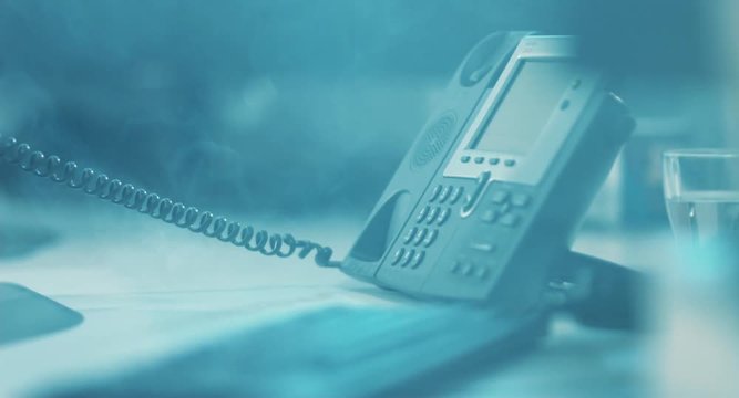 Emergency situation in office of big business center. Employee answering phone and putting the phone on desk with irritation.