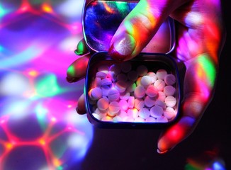 A young woman with nice nails offers ecstasy on a disco. - obrazy, fototapety, plakaty