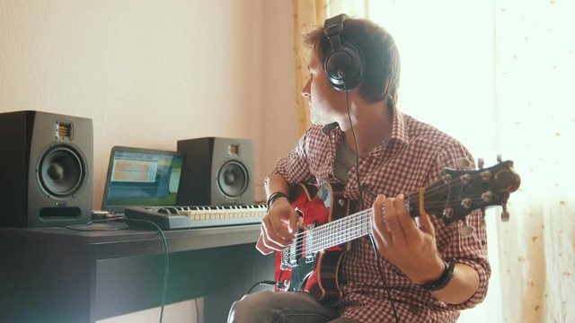 Young musician composes and records soundtrack playing the guitar using computer and keyboard