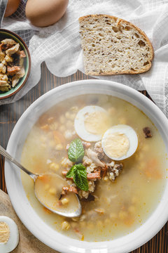 Healthy and warming winter soup with rice, carrot, chickpeas, chicken, ham and boiled egg over rustic background. Spanish soup (Puchero Andaluz). Top view. Winter food concept