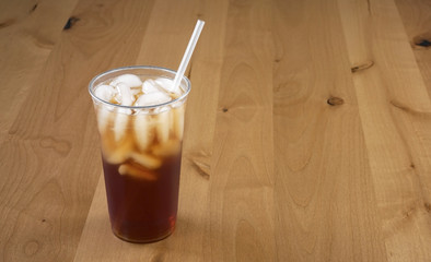 Fresh Brewed Ice Tea in a clear cup and straw on a wood background.