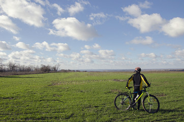 Obraz premium man with a bicycle on a green field