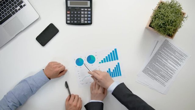 Businessmen analising diagrams in the office. View from the top of men's hands. Close-up shot.