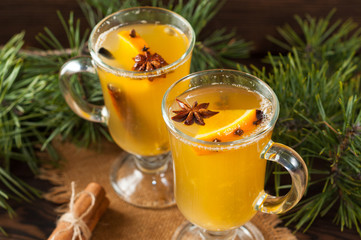 White mulled wine with various spices on a wooden background. Hot alcoholic beverage