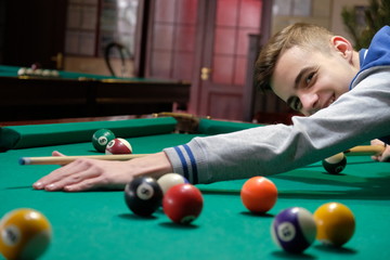 Teen playing in american pool billiard.