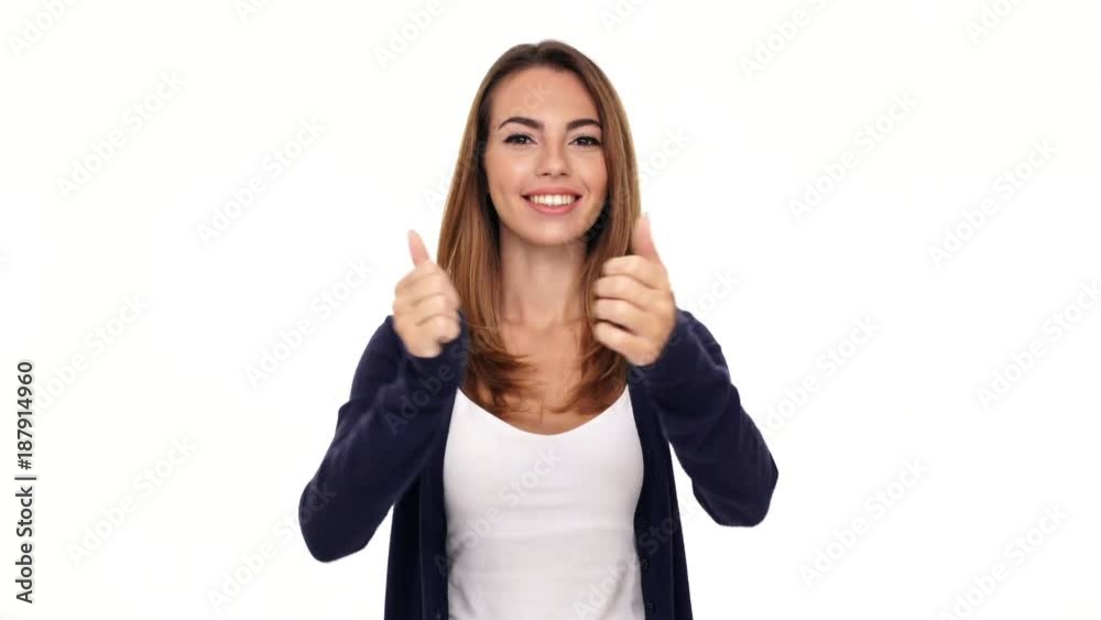 Wall mural happy brunette woman showing thumbs up at the camera over white background