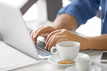 Young blogger using laptop in cafe, closeup