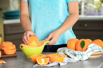 Woman making orange juice in kitchen