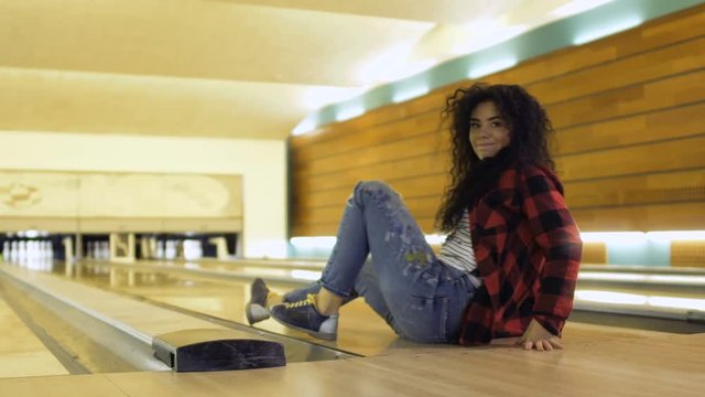 Pretty woman throws bowling ball and falls down on the path
