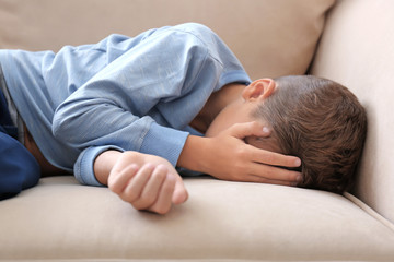 Fototapeta na wymiar Depressed little boy crying on couch at home