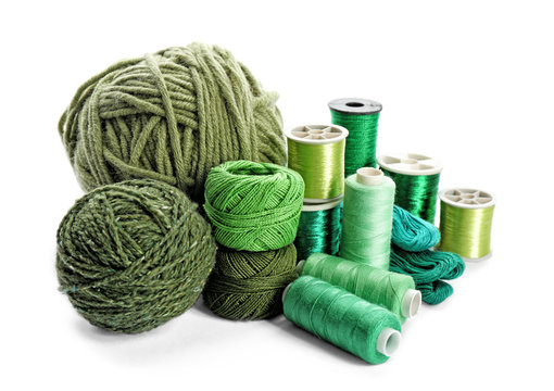 Green threads of different shades on white background