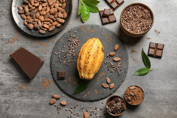 Composition with cocoa pod and products on grey background, top view