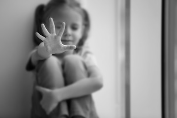 Sad little girl making stop gesture indoors, black and white effect