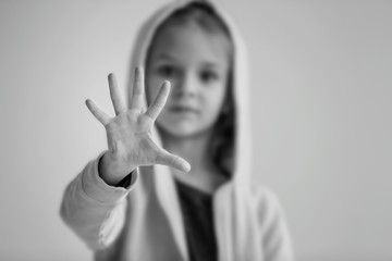 Sad little girl making stop gesture on grey background, black and white effect