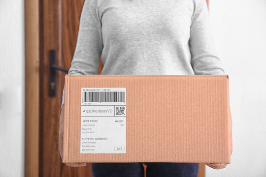 Woman holding parcel box near door, closeup