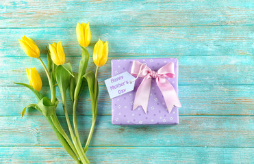 Composition with gift box and flowers for Mother's Day on color wooden background