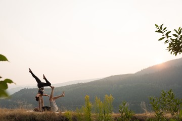Sporty couple practicing acro yoga in a lush green ground