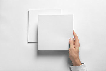 Man holding blank sheet of paper on white background. Mock up for design