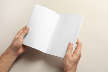Man holding brochure with blank pages on light background. Mock up for design