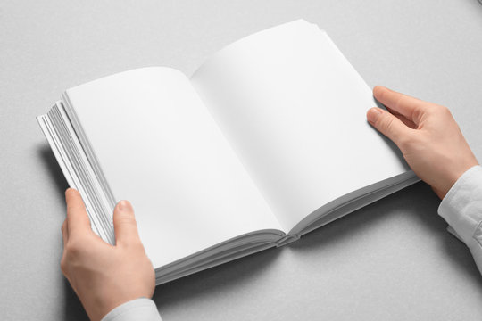 Woman holding book with blank pages on light background. Mock up for design