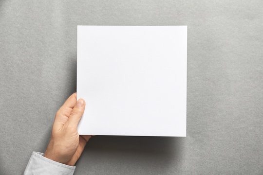 Man holding blank sheet of paper on grey background. Mock up for design