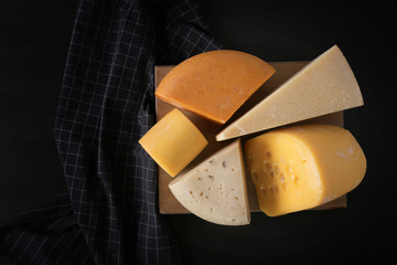 Wooden board with different kinds of delicious cheese on table
