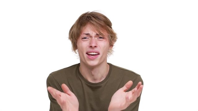 Portrait of blond guy being upset and isolated over white background screaming why touching head in slow motion. Concept of emotions