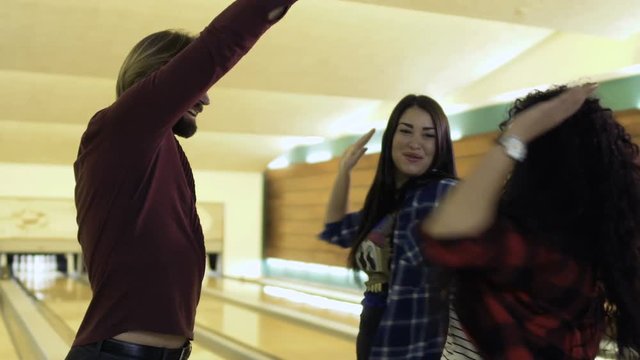 Friends high-fiving to each other at the bowling club