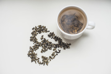 white cup of fragrant tea on white background with heart from tea
