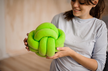 Smiling woman holding a cute green knot pillow