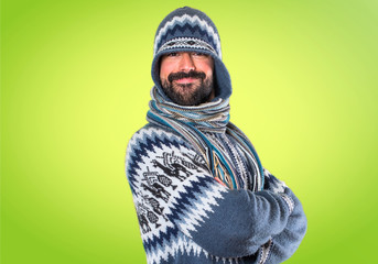 Man with winter clothes with his arms crossed on colorful background