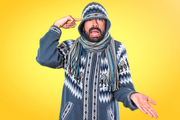Man with winter clothes making crazy gesture on colorful background